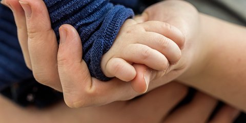 Erwachsene Hand hält die eines Babys